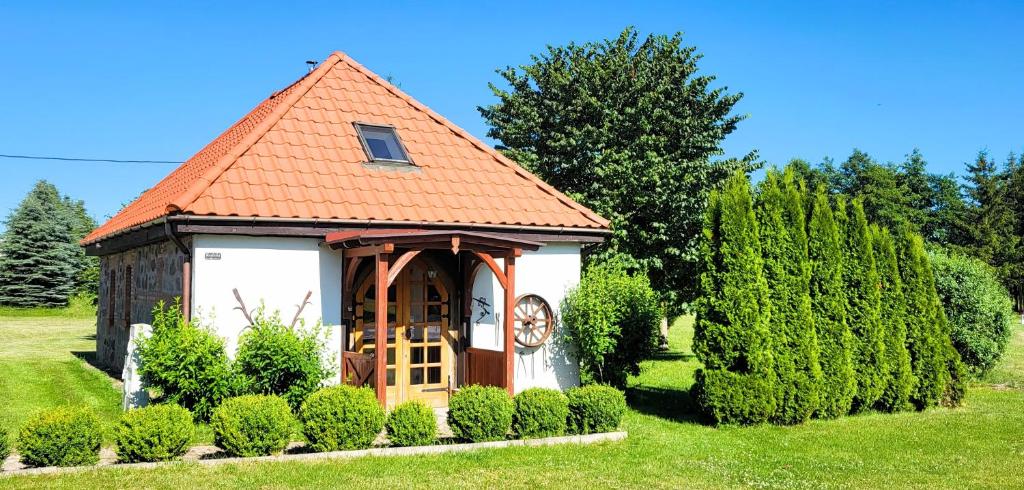 a small building with a clock on it in a yard at Kuźnia-Grodno in Krzywa Wieś