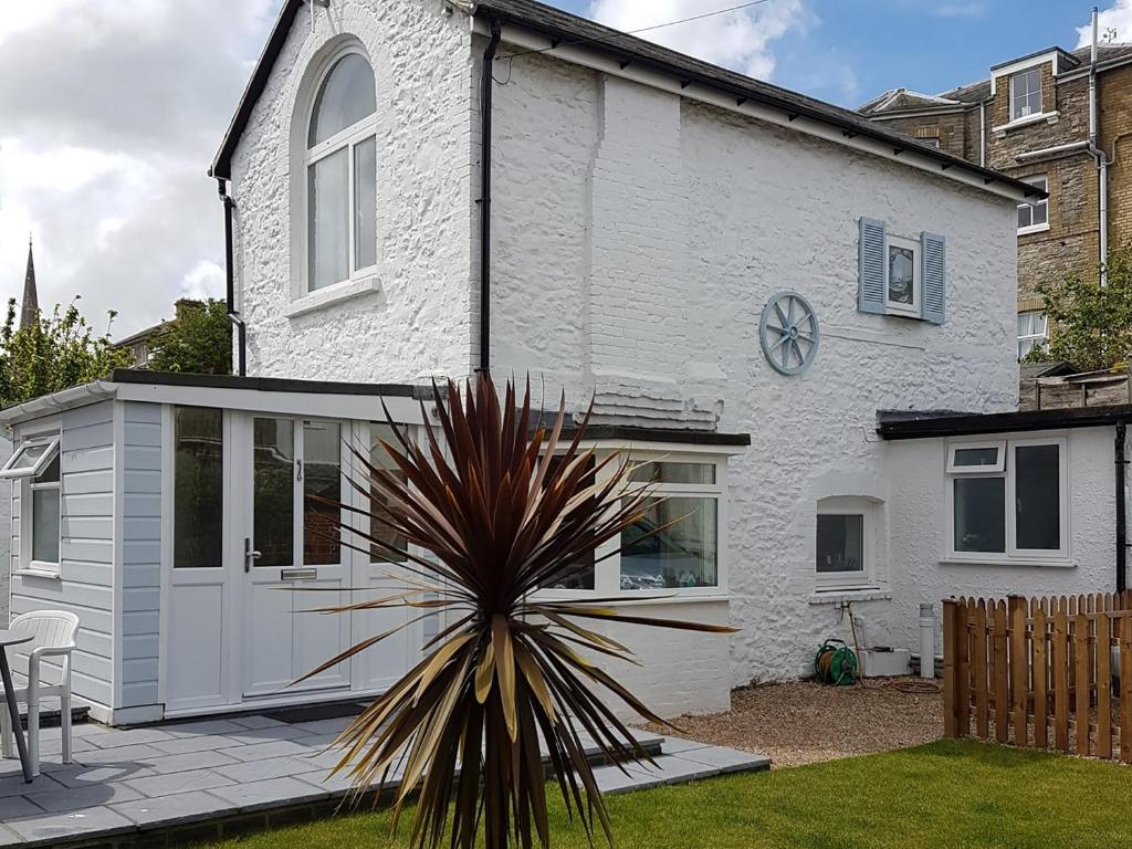 a white house with a palm plant in front of it at Little Dover Cottage in Ryde
