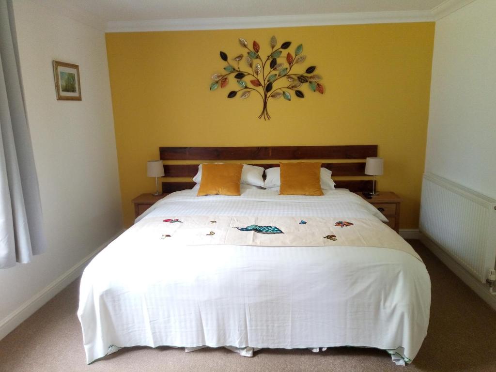 a bedroom with a large white bed with yellow walls at Bartles Lodge in Elsing