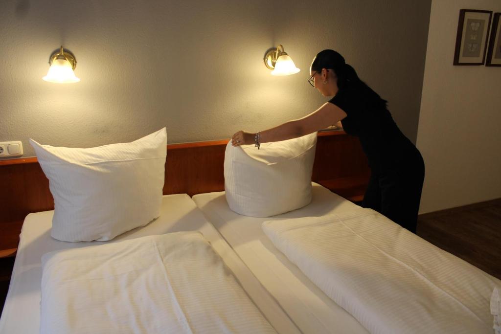 a woman making two beds in a hotel room at Hotel Eisenbahn in Karlstadt