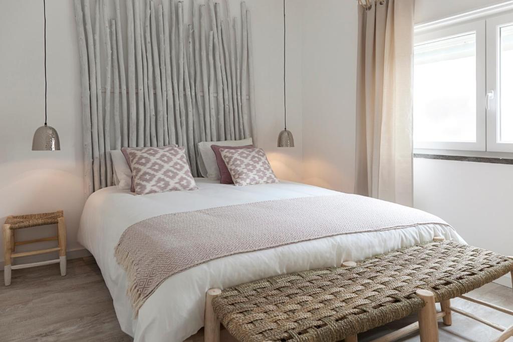 a bedroom with a bed with a bench and a window at Mare Cheia (High Tide) Beach and Surf Apartments in Peniche