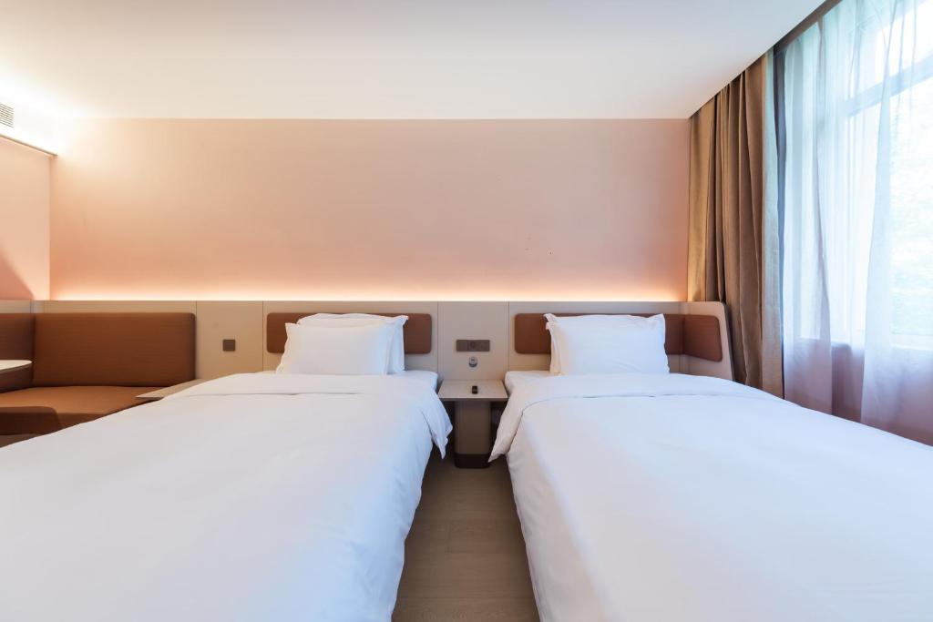 two beds in a hotel room with a window at Hanting Hotel Beijing Mudanyuan Subway Station in Beijing