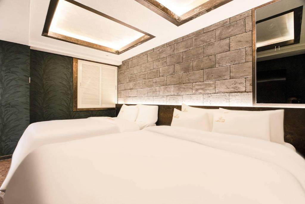 two white beds in a room with a brick wall at hotel louize in Seoul