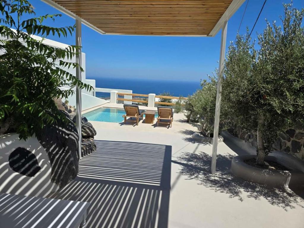 a patio with chairs and a pool and the ocean at Splendour Hotel and Suites in Firostefani