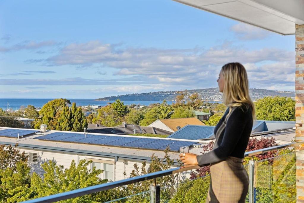 Una mujer parada en un balcón con vistas a la ciudad en The Dromana Beach House - Stunning Views, en Dromana