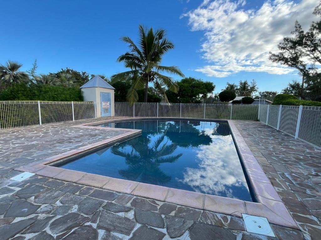 Saint-PaulにあるT2 duplex- piscine- vue merの柵とヤシの木がある庭のプール