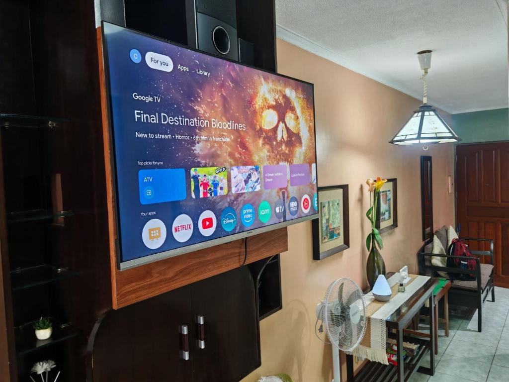 TV de pantalla plana colgada en la pared de la sala de estar. en Cozy Condo in Baguio, en Baguio