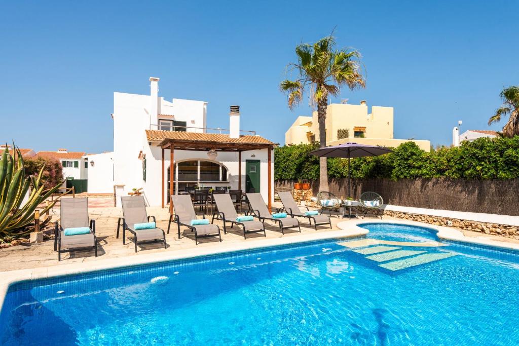 a swimming pool with chairs and a villa at Brisa Marina in Cala en Blanes