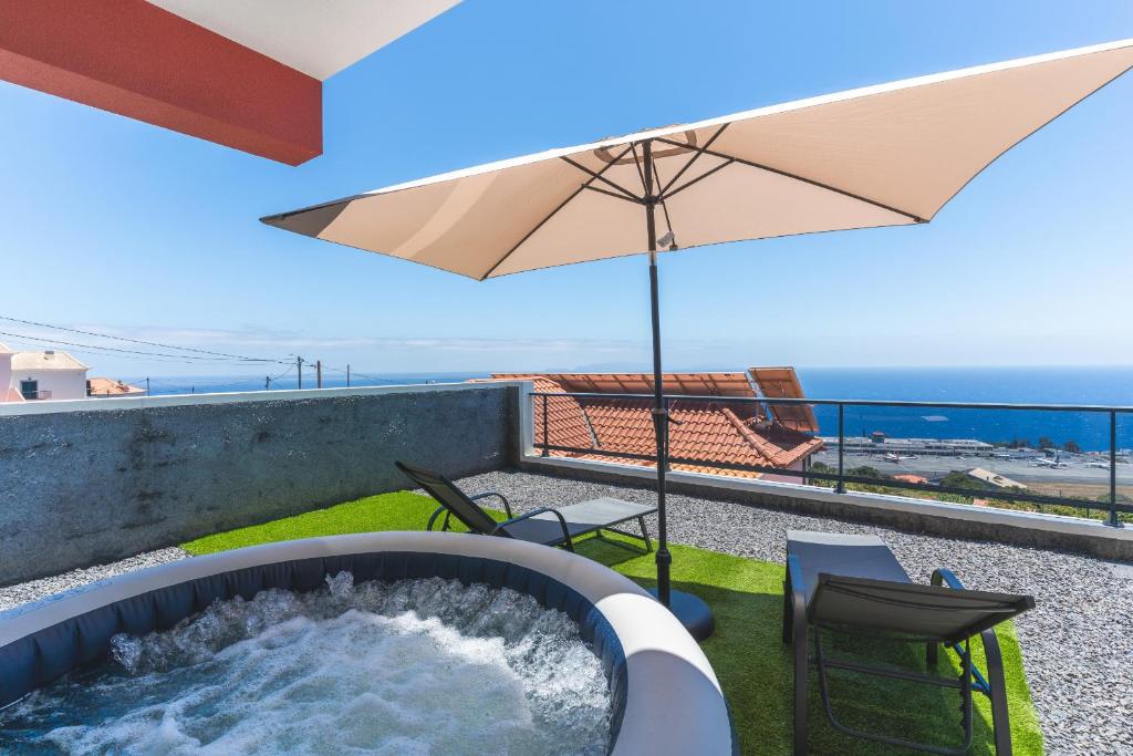 a hot tub on a balcony with an umbrella at Blue Outlook View by Atlantic Holiday in Água de Pena
