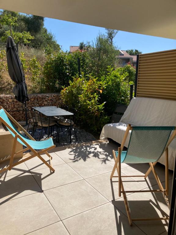 un patio avec deux chaises, une table et un parasol dans l'établissement Clairière du Cap Brun, à Toulon