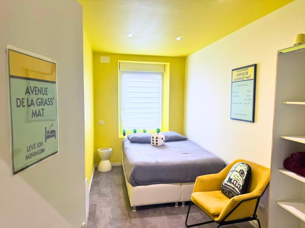 a yellow room with a bed and a chair at Le Moonhomepoly, proche centre ville et gare in Mulhouse