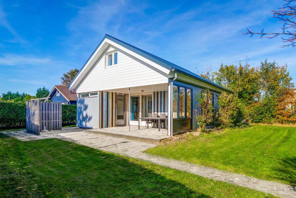 ein kleines Haus mit Rasen davor in der Unterkunft Vakantiehuis De Strandloper - Julianadorp aan Zee in Julianadorp