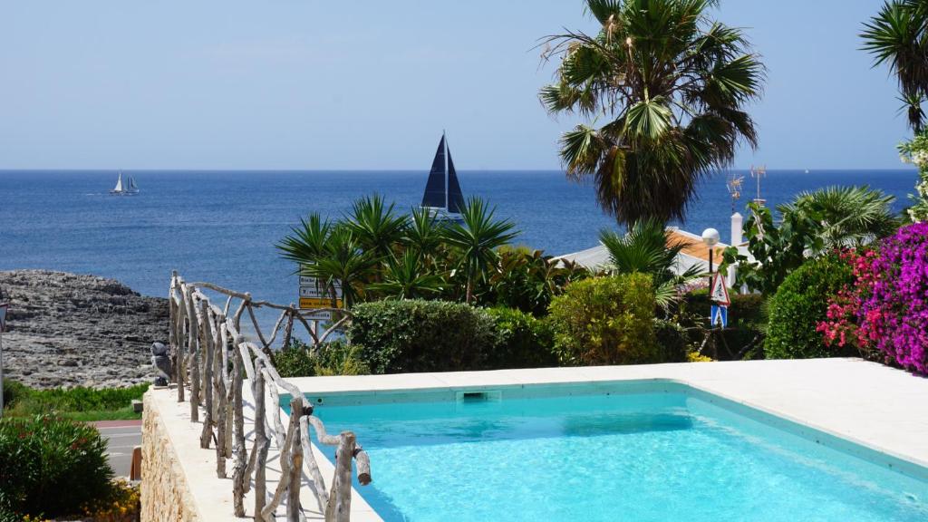 Ein Swimmingpool mit dem Meer im Hintergrund in der Unterkunft Villa en primera linea de mar cerca de Binibeca in Sant Lluís