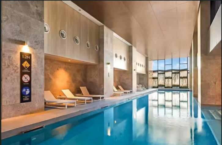 a large swimming pool with chairs and a swimming pool at 2-Bedroom Apartment in Melbourne CBD with Balcony, Pool & Gym Access in Melbourne