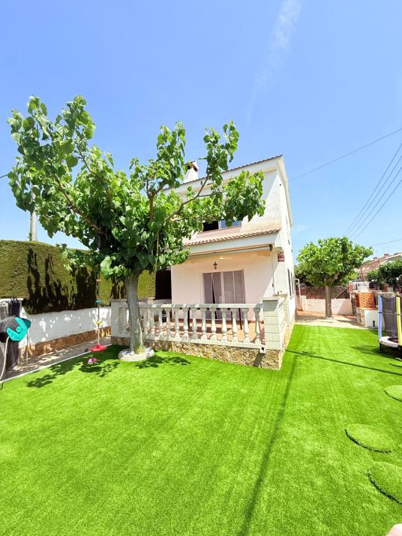 a green yard with a house and a tree at Villa del sol in Creixell