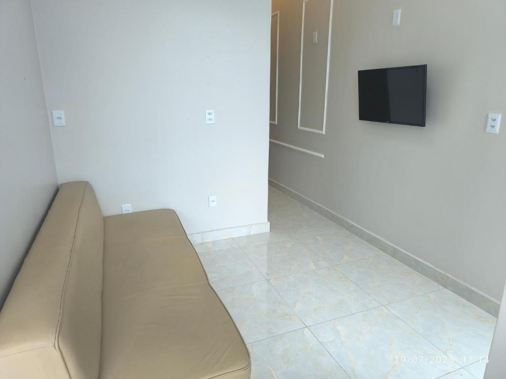 a couch in a room with a tv on a wall at Apto Lindo e Aconchegante 3 in Manaus