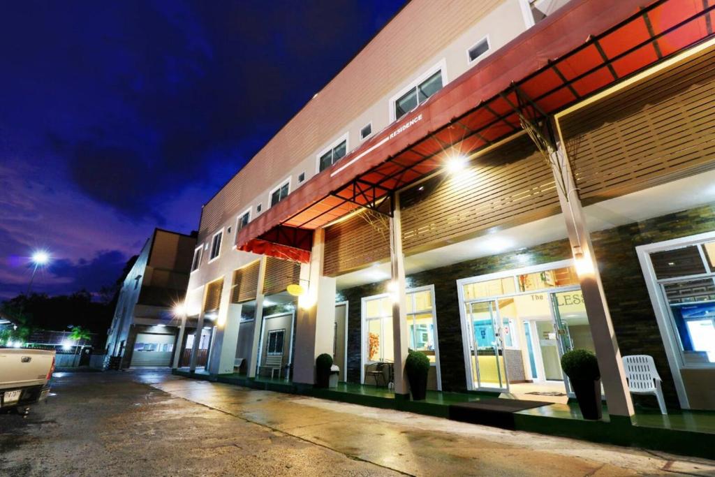 Un edificio con un estacionamiento enfrente por la noche. en The Bless Residence, en Hat Yai