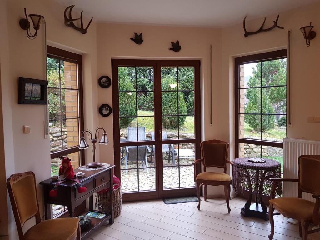 ein Wohnzimmer mit Türen sowie einem Tisch und Stühlen in der Unterkunft Mikołajówka - przytulny dom z widokiem in Świeradów-Zdrój