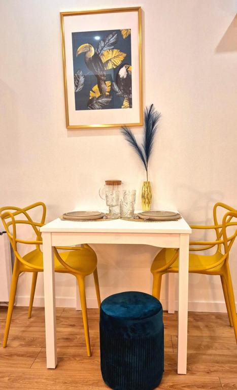 une table blanche avec deux chaises jaunes et une table avec un tabouret bleu dans l'établissement Le Moderne - Wifi - Near train station, à Reims