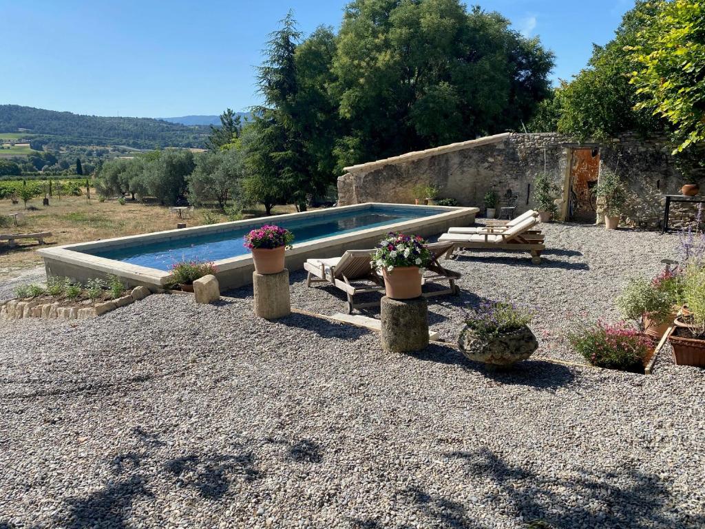 a swimming pool with potted plants in a gravel yard at Le Domaine Saint Jean in Saint-Saturnin-les-Apt