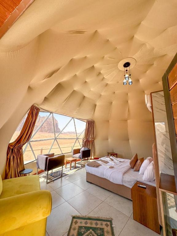 a bedroom with a bed and a large window at Beauty Wadi Rum Luxury Camp in Wadi Rum