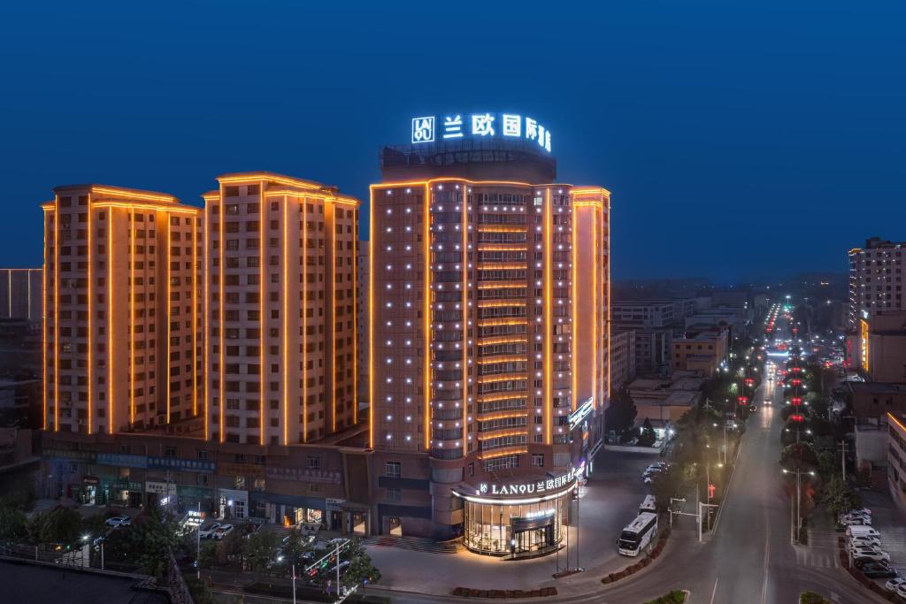 a lit up building in a city at night at Lan Ou International Hotel Atushi in Artux