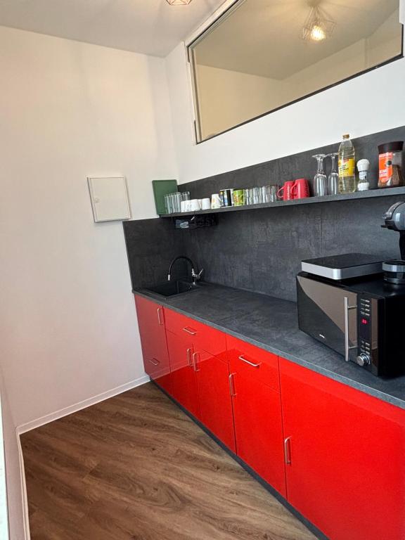 a kitchen with red cabinets and a black counter top at Top Appartement in Bremerhaven