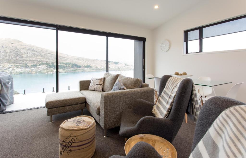 ein Wohnzimmer mit einem Sofa, Stühlen und Fenstern in der Unterkunft Highland Views in Queenstown