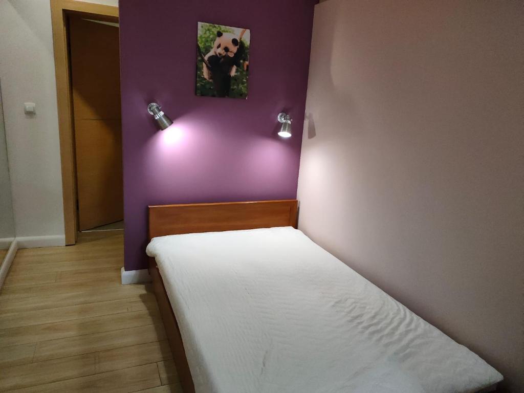 a bedroom with a bed with a purple wall at 1904 Loft in Świnoujście
