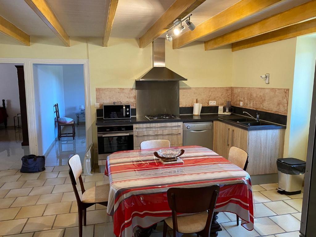 a kitchen with a table with chairs and a stove at Les Tilleuls in Tréjouls