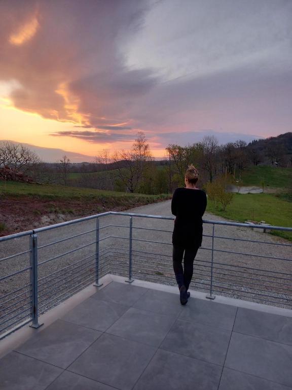 a person walking on a balcony looking at the sunset at Gite Le Sauvage in Sébrazac