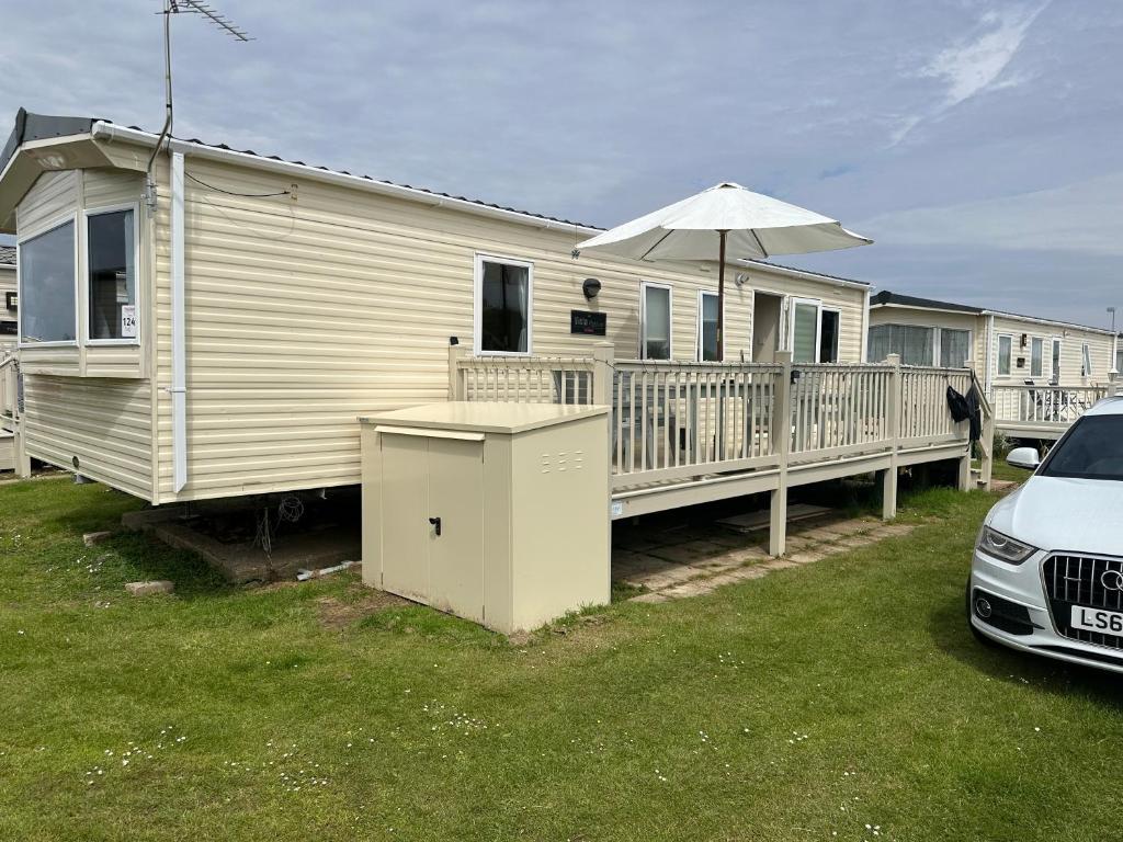 a mobile home with an umbrella and a car at Your Happy Place - 8 Berth Caravan 5 minutes from lovely sandy beach in Heacham