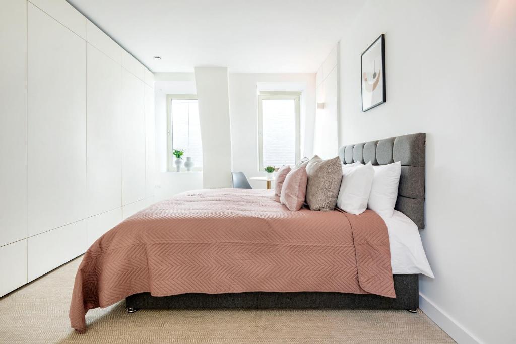 una camera da letto con un grande letto e pareti bianche di Hounslow Central Studio Aparments a Hounslow