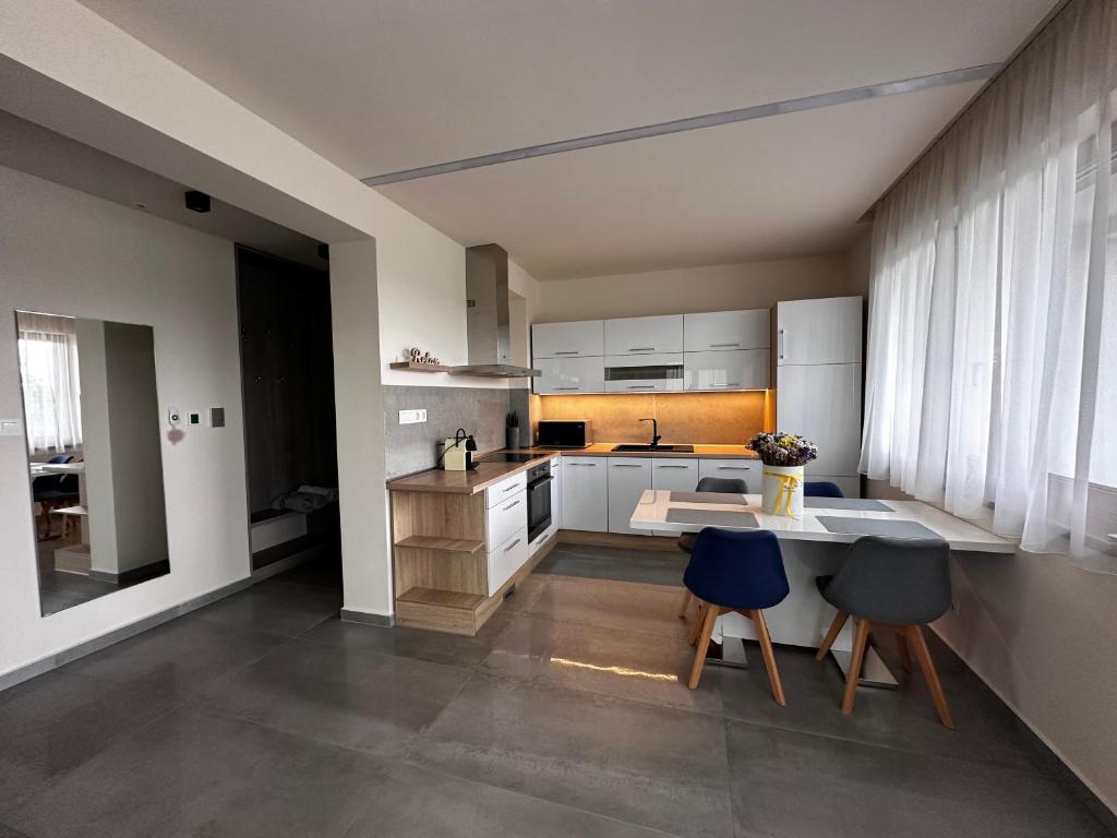 a kitchen with white cabinets and blue chairs at Gamma Apartmanok és Jakuzzi in Miskolctapolca