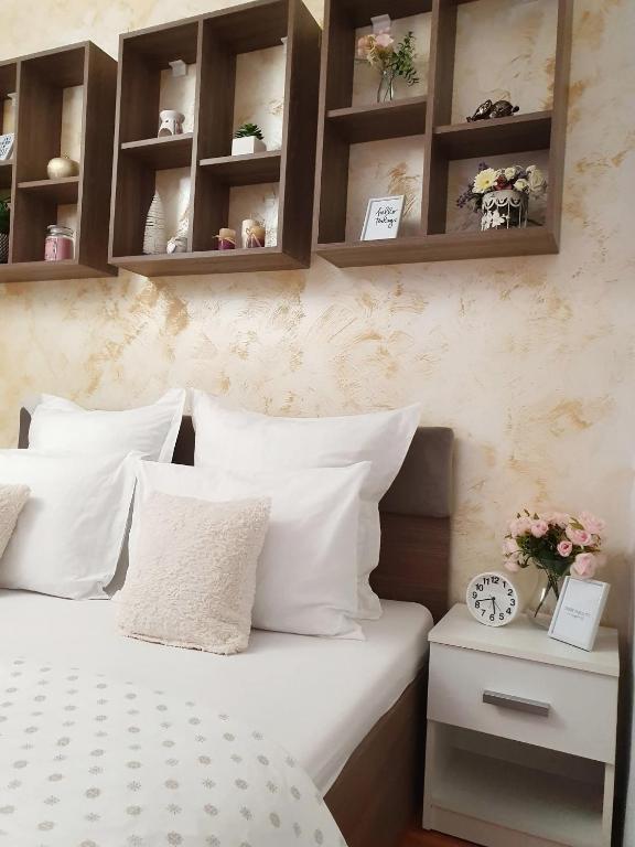 a bedroom with a bed with white pillows and shelves at Ra Apartment in Oradea