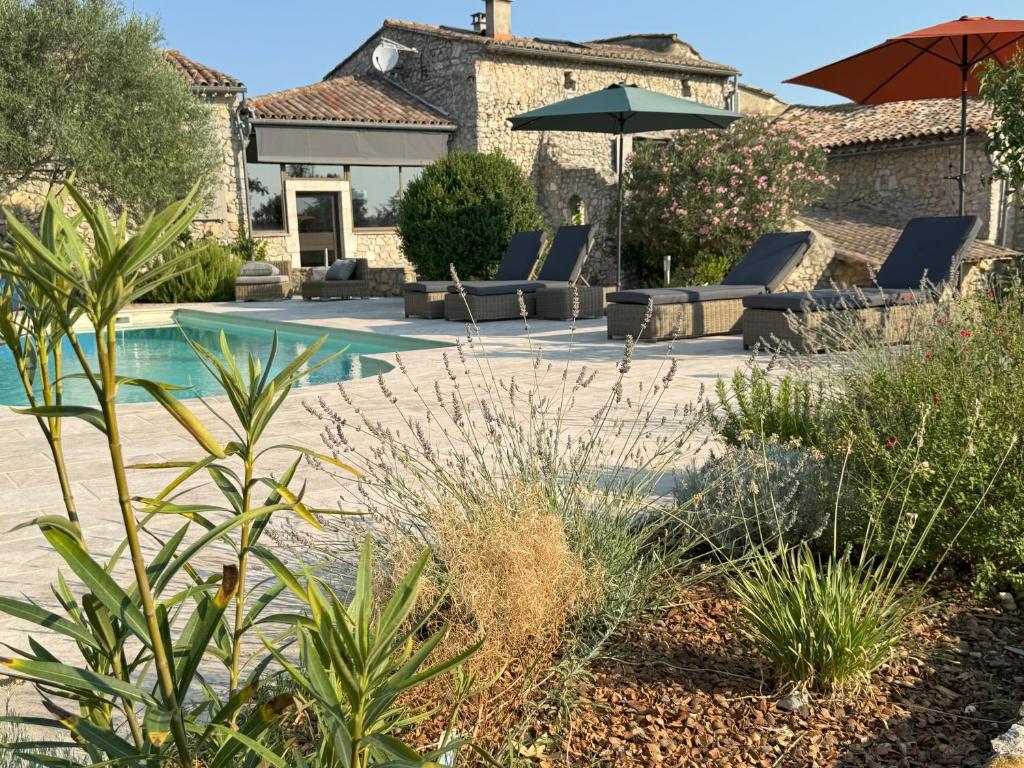 a pool with chairs and an umbrella in a yard at Maison Casamande & SPA - Luxe et sérénité dans un domaine d'amandiers in Bouquet