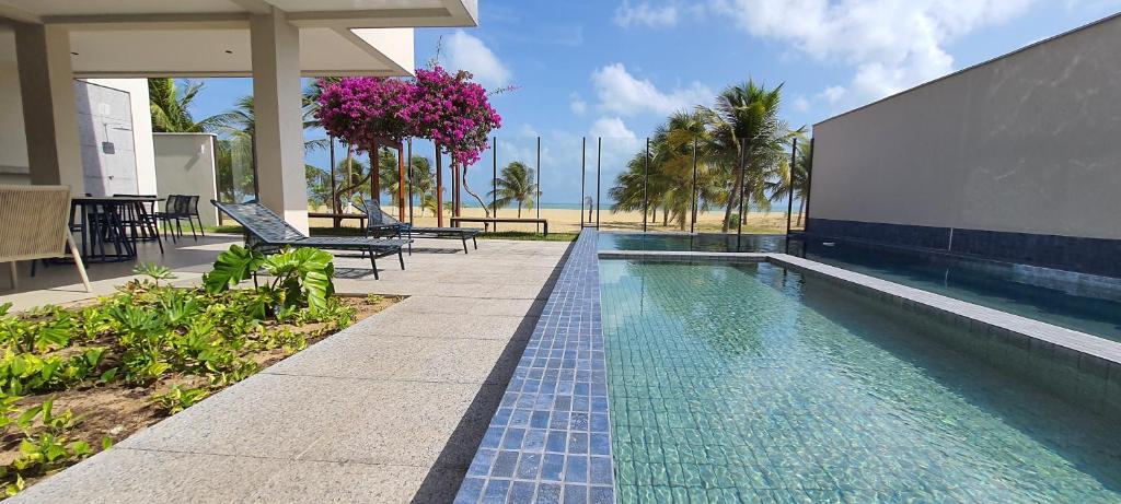 una piscina accanto a un edificio con palme di The Home São Miguel do Gostoso Apt 006 a São Miguel do Gostoso