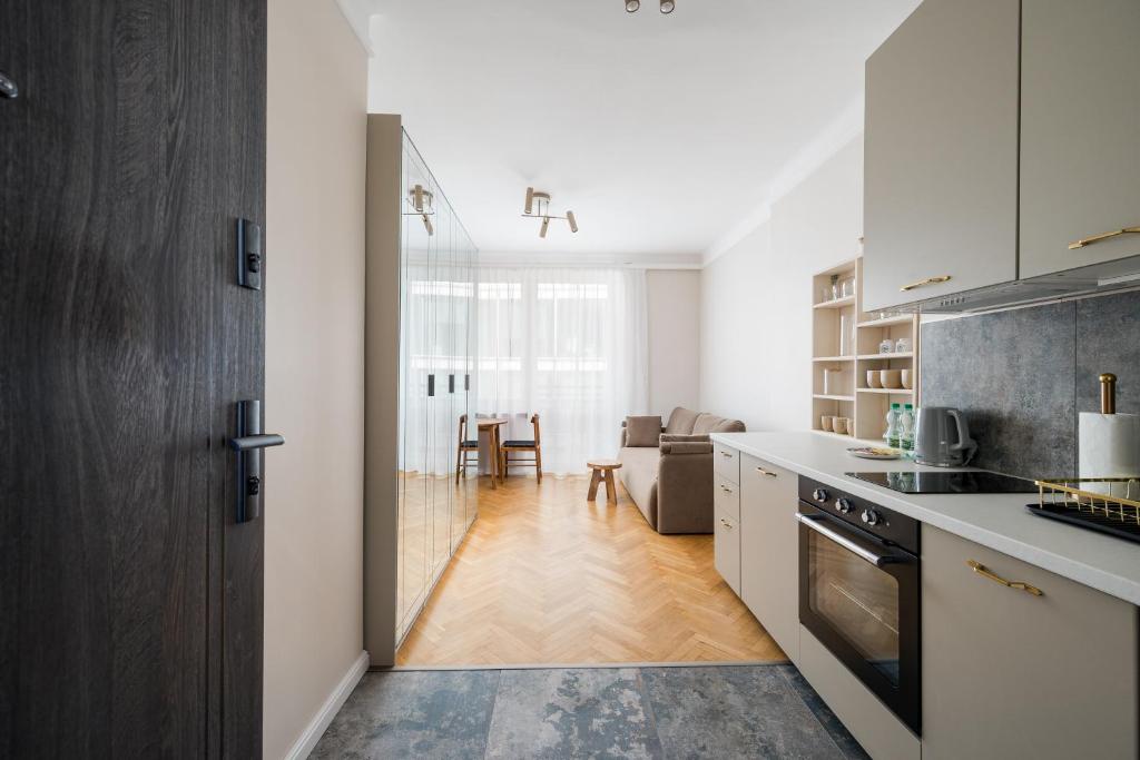 a kitchen with white cabinets and a living room at Widok Warsaw City Apartment by BookingHost in Warsaw