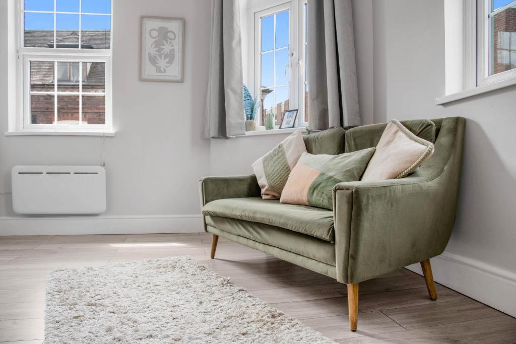 a green couch in a living room with windows at WhiskAwayHomes - Taylor Bennett - Apartment 3 in Worcester