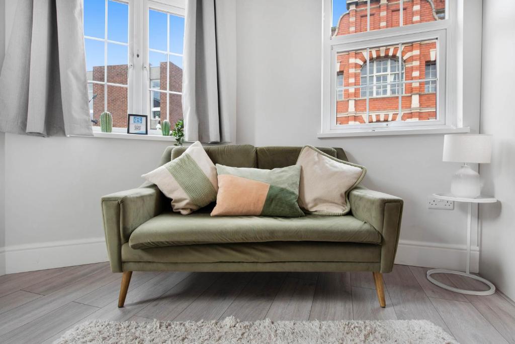 a green couch in a living room with two windows at WhiskAwayHomes TaylorBennett Apartment 3 in Worcester
