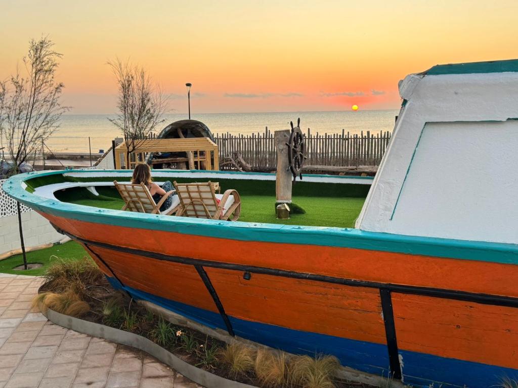 a woman sitting in a boat on the grass at The Boat House - Beachfront Garden Home in Mareny Barraquetas