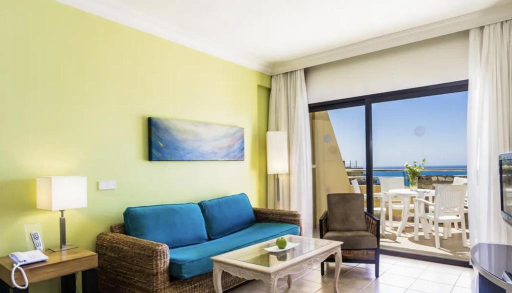 a living room with a blue couch and a view of the ocean at Apartamento Espectacular con Vistas al Mar en Bahía Feliz in Playa del Aguila