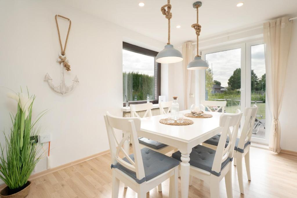 a white dining room with a white table and chairs at Landhaus Ostseeglück in Dahme