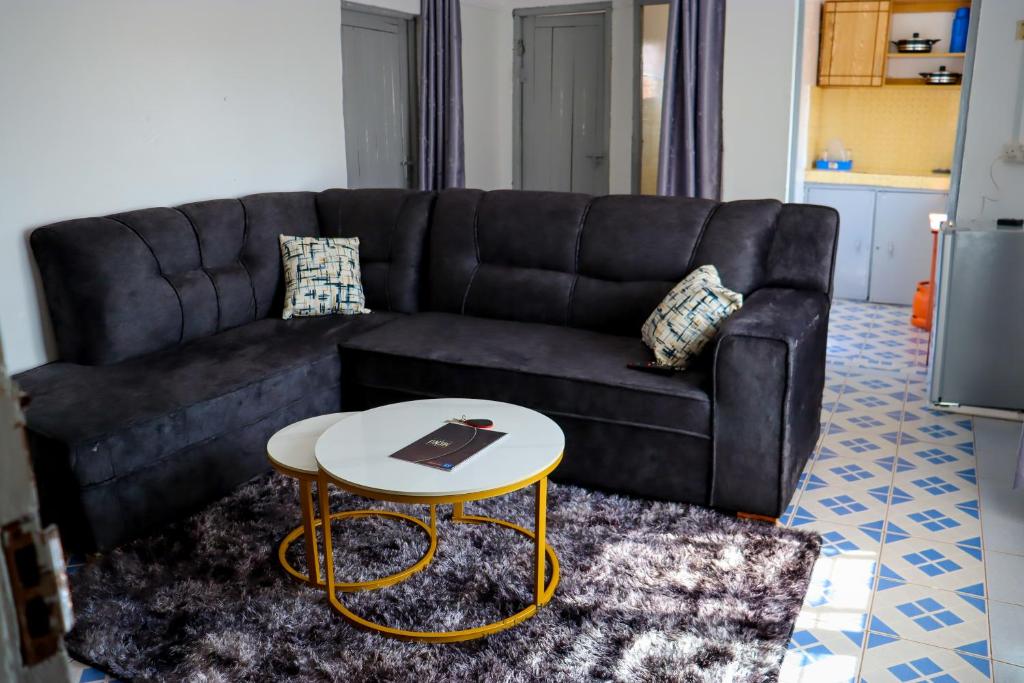a living room with a black couch and a table at Kristina Homes 1&2 Bedroom Apartment in Voi