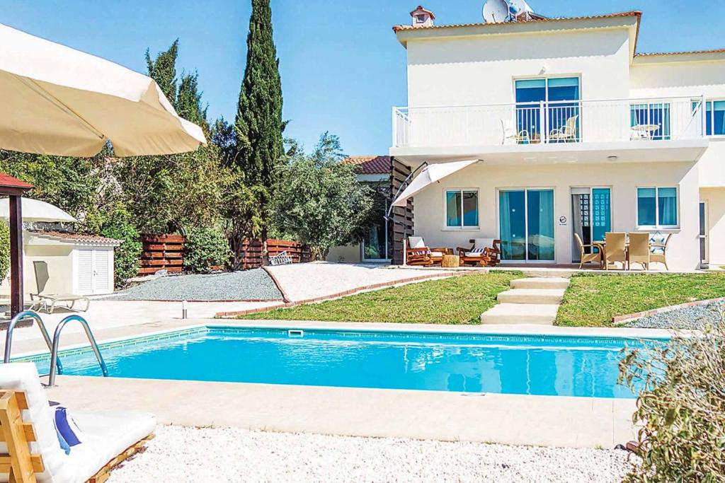 a villa with a swimming pool in front of a house at Villa Elena Coral in Peyia
