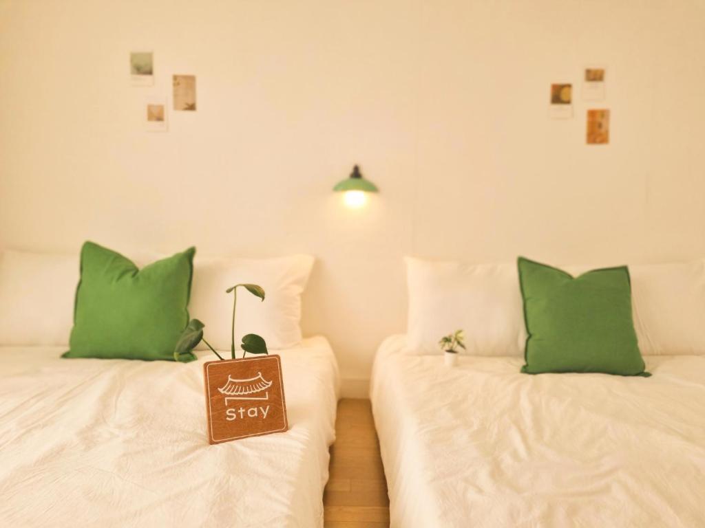 two beds with green pillows with a sign that says stay at N-Stay#CozySpace#Pyeongtaek Station#Bus Terminal#K6 Humphreys#Samsung in Pyeongtaek