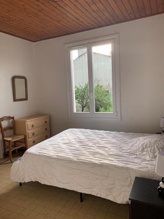 a bedroom with a white bed and a window at L'Albizia - Chambre chez l'habitant in La Tranche-sur-Mer