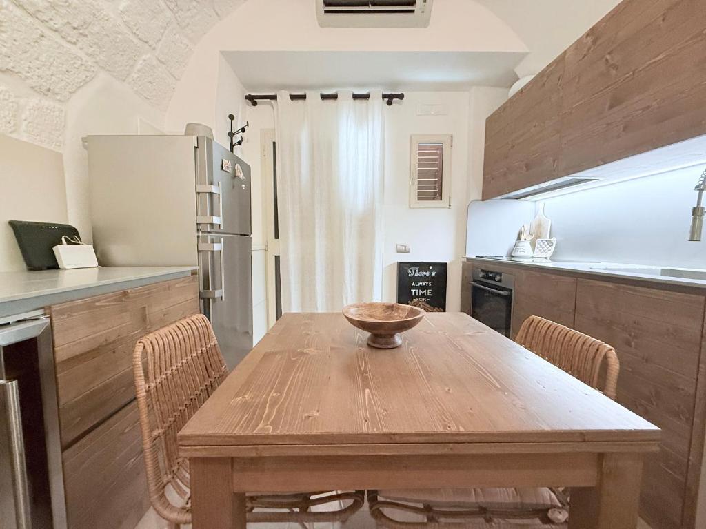a kitchen with a wooden table with chairs and a refrigerator at Suite Salgemma in Polignano a Mare