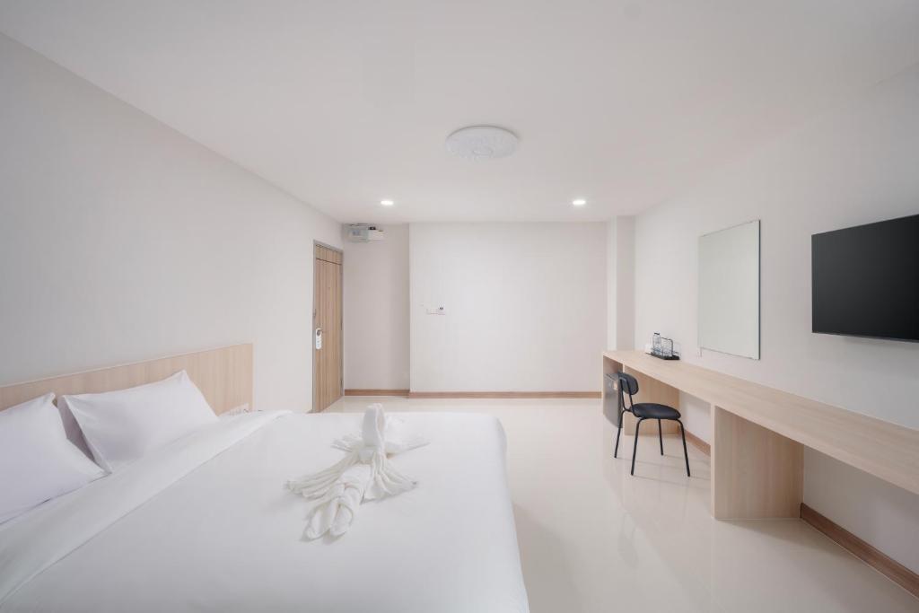 a white bedroom with a white bed and a tv at Cloud9 Stay Chiang Mai in Chiang Mai