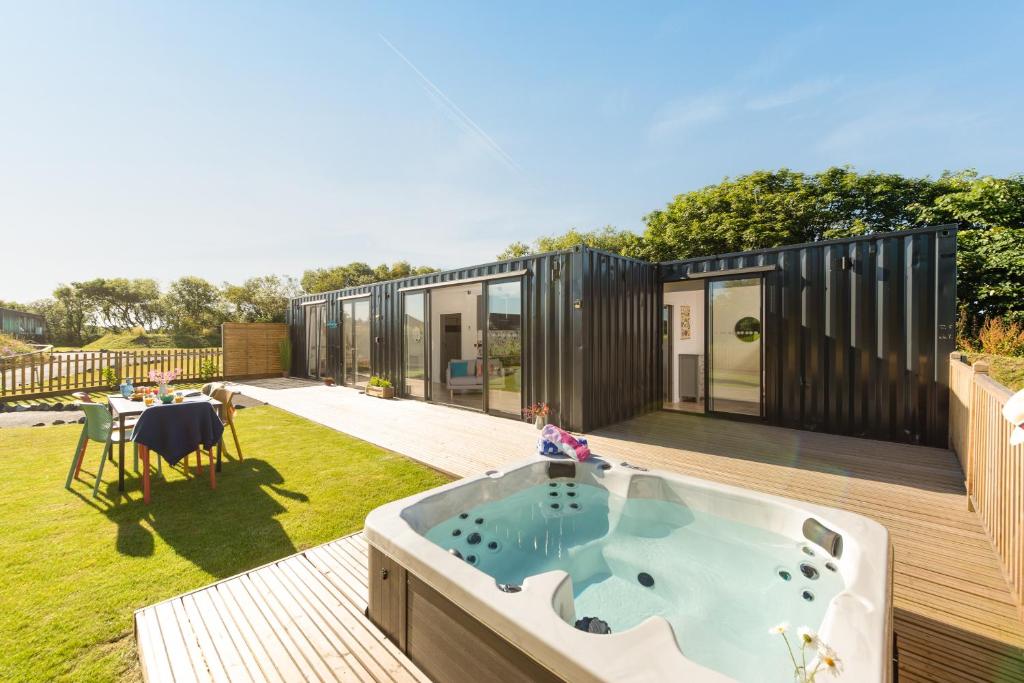 a small house with a tub on a deck at Trevassack Holidays in Helston